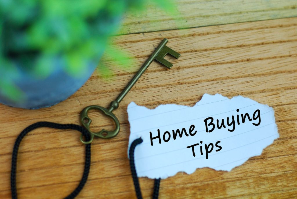 "Home Buying Tips" on a piece of paper with an old fashioned key on wooden background